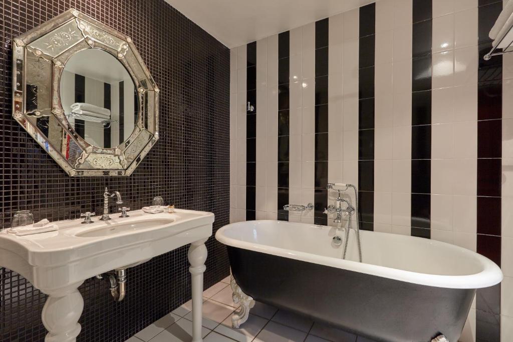 - une salle de bains en noir et blanc pourvue d'une baignoire et d'un lavabo dans l'établissement Hôtel du Petit Moulin, Haute Couture hotel by Lacroix, à Paris