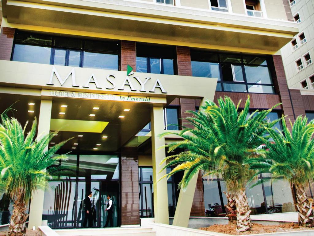 a large building with palm trees in front of it at Masaya By Emerald in Erbil