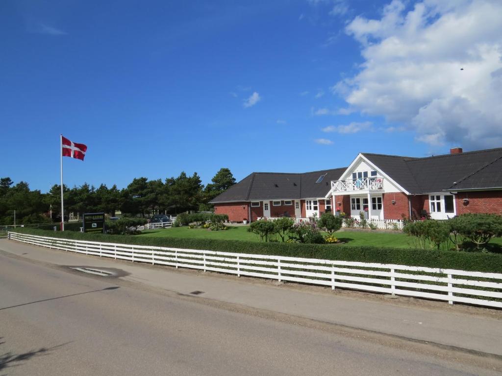 a house with a white fence on the side of a road at Motel Garni Blåvand in Blåvand
