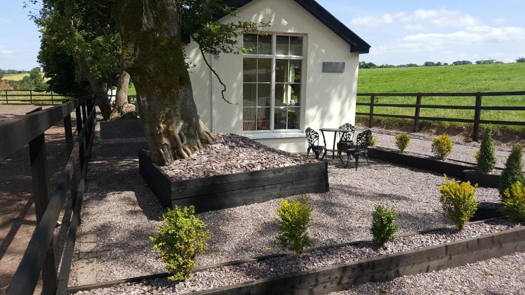 a house with a tree and a bench next to a fence at The Stable Lodge Cannaway House in Macroom