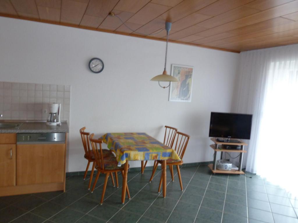 eine Küche mit einem Tisch und Stühlen sowie einem TV in der Unterkunft Wangeroogeweg 3a in Wangerland