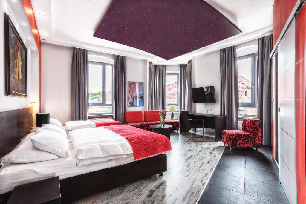 a bedroom with a large bed with a red blanket at Grand Boutique Hotel - dawny Hotel Kaliski Ratuszowy in Rzepin