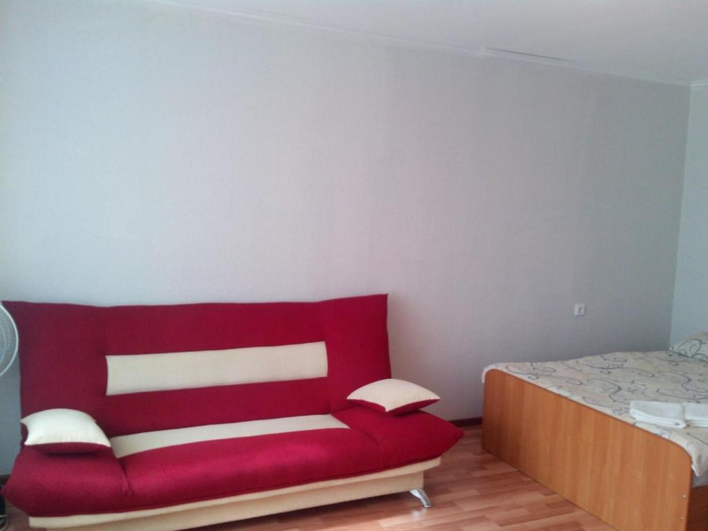 ステルリタマクにあるApartment "Kvartirniy Vopros" Yurmatinskaya 8のベッド付きの客室内の赤いソファ