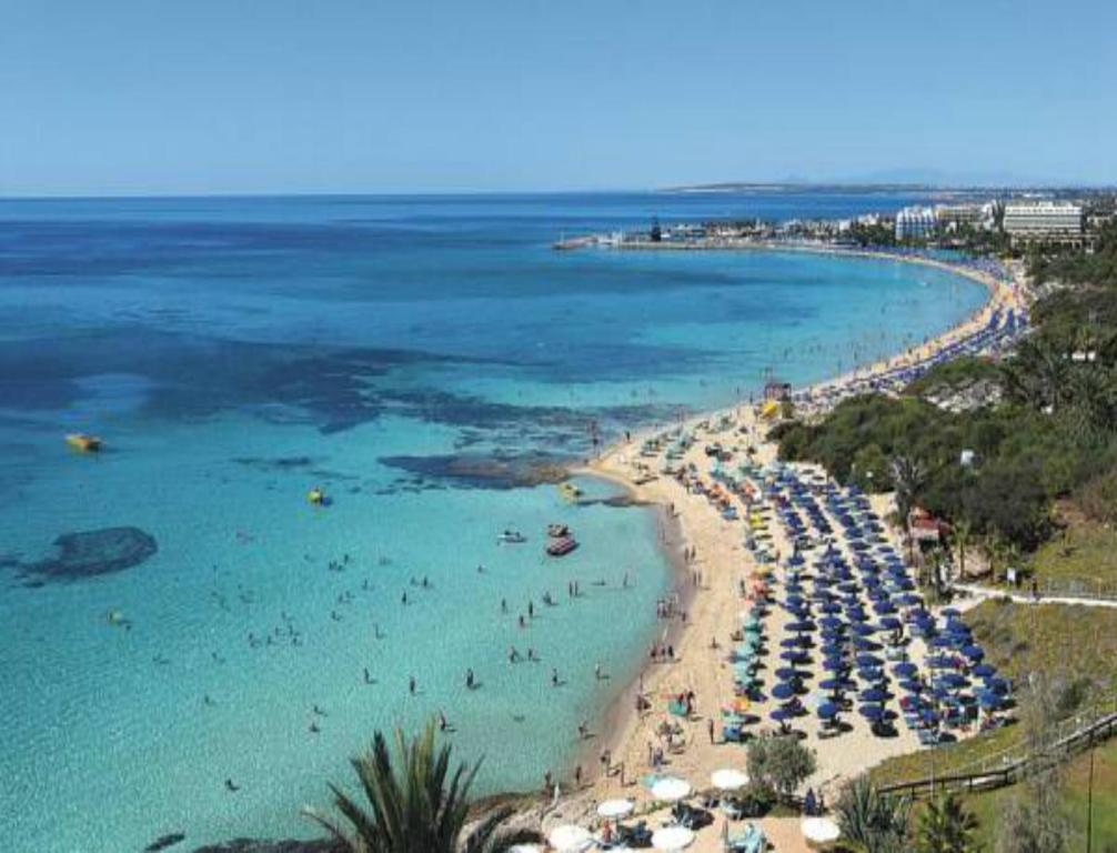 a beach with umbrellas and people in the water at Mon Repos Hotel in Ayia Napa