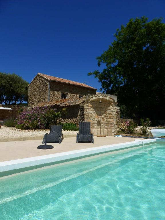 une maison avec deux chaises à côté d'une piscine dans l'établissement mas de costebelle, à Bollène