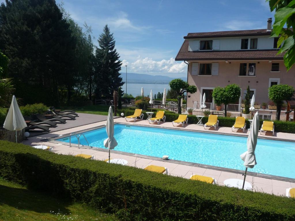 a swimming pool with chairs and umbrellas next to a house at L'Oasis in Évian-les-Bains