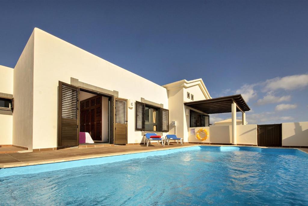 eine Villa mit einem Pool vor einem Haus in der Unterkunft Los Charcones vivienda vacacional in Playa Blanca