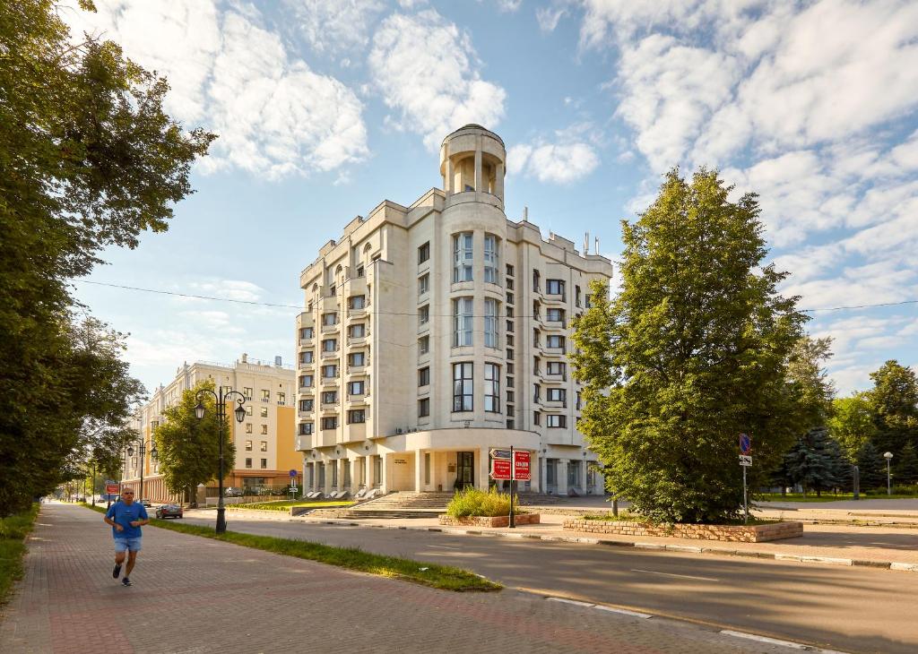 
a person walking down a street next to a tall building at Oktyabrskaya Hotel in Nizhny Novgorod
