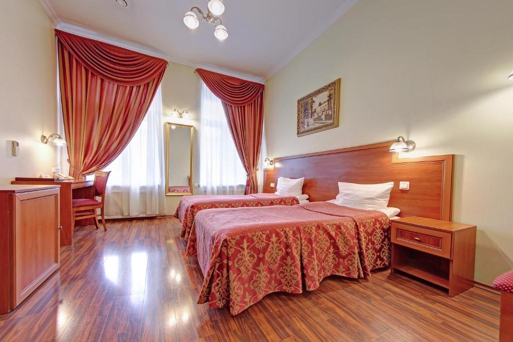 a hotel room with two beds and a desk at Atria Guest House in Saint Petersburg