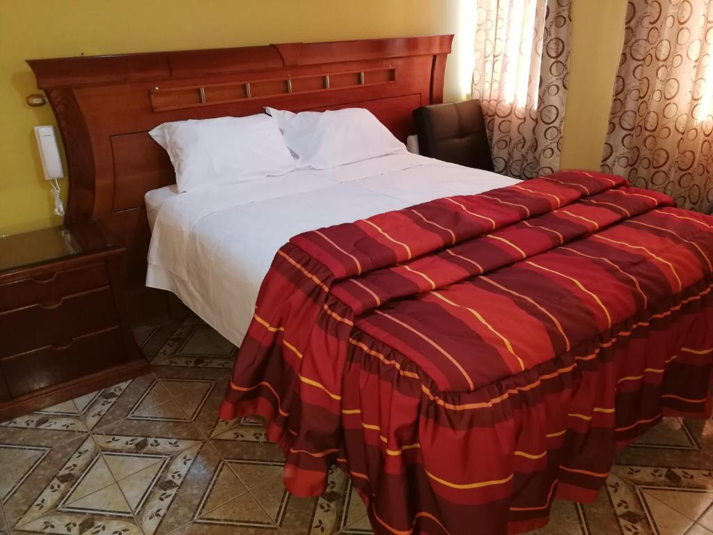 Un dormitorio con una cama con una manta roja. en Hostal El Imperio, en Arequipa