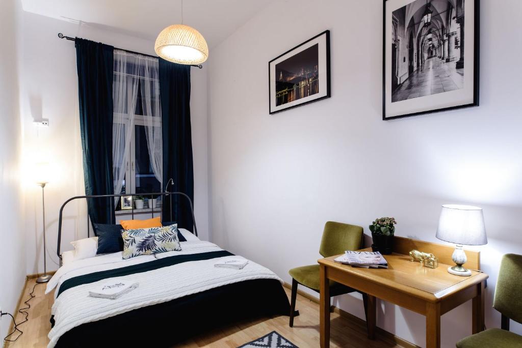 1 dormitorio con cama, mesa y escritorio en Golden Lion Guest Rooms Szewska 19, en Cracovia
