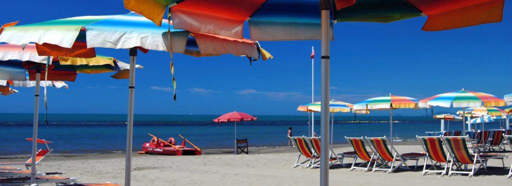 a group of beach chairs and umbrellas on a beach at Lagomare Puccini in Torre del Lago Puccini