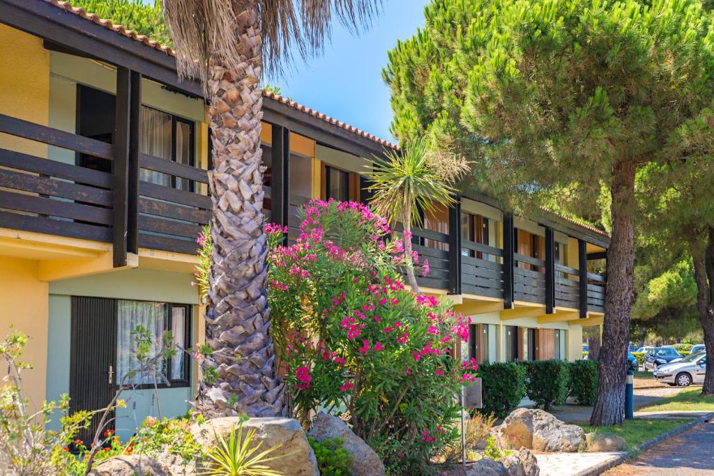 een gebouw met bomen en bloemen ervoor bij Azureva Cap d'Agde in Cap d'Agde