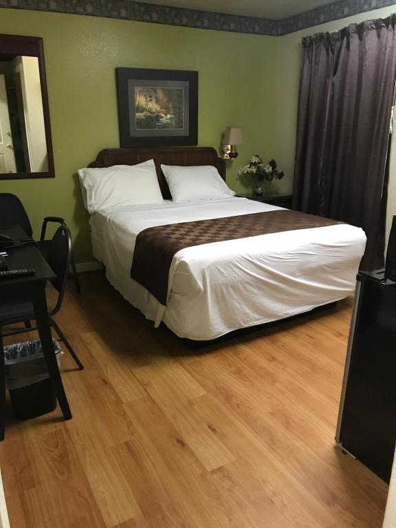 een slaapkamer met een groot bed en een houten vloer bij Outpost Motel in Dripping Springs