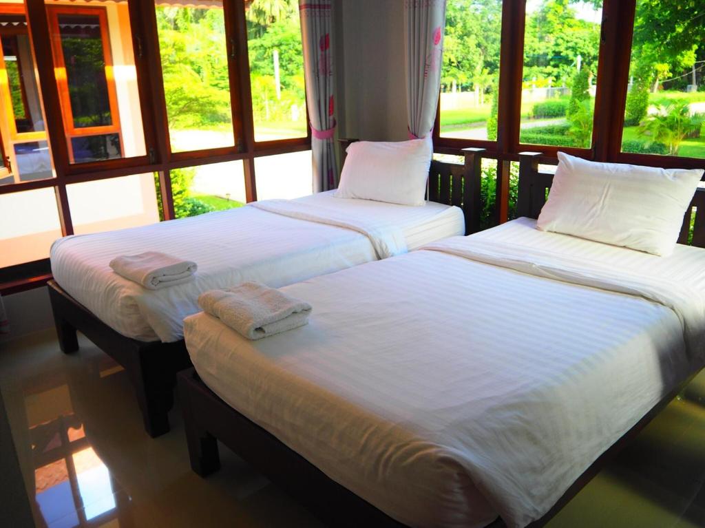 two twin beds in a room with large windows at Bansuansiriwat in Ban Tak