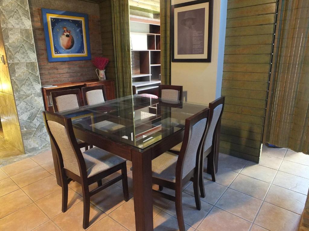 uma sala de jantar com uma mesa de vidro e cadeiras em Casa Camelia em Rinconada de los Andes