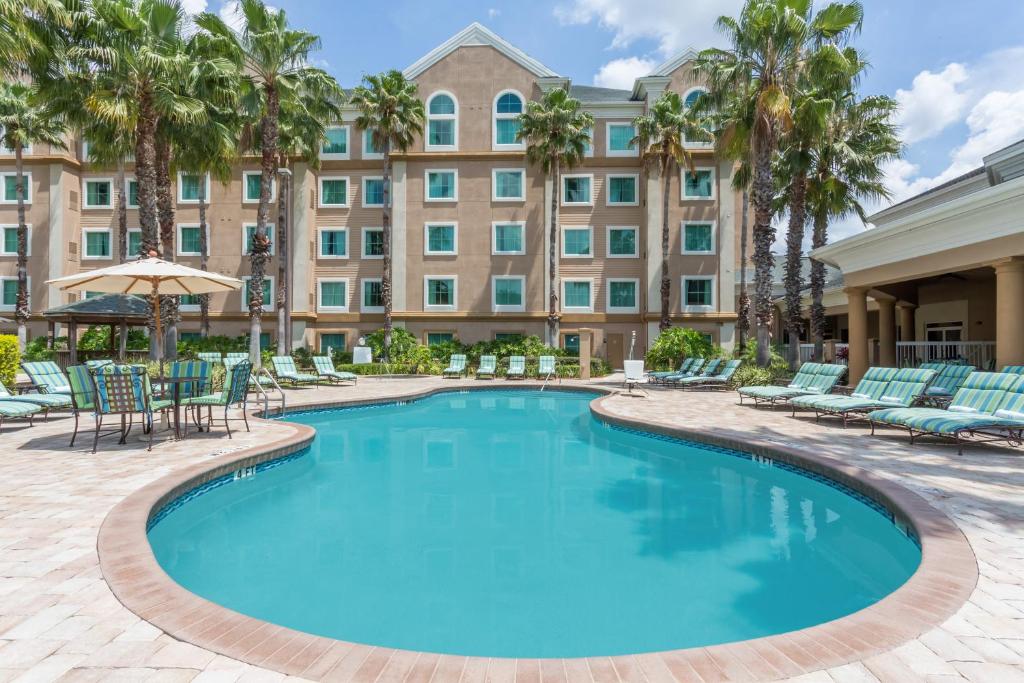 uma piscina com cadeiras e um hotel ao fundo em Hawthorn Suites by Wyndham Lake Buena Vista, a staySky Hotel & Resort em Orlando