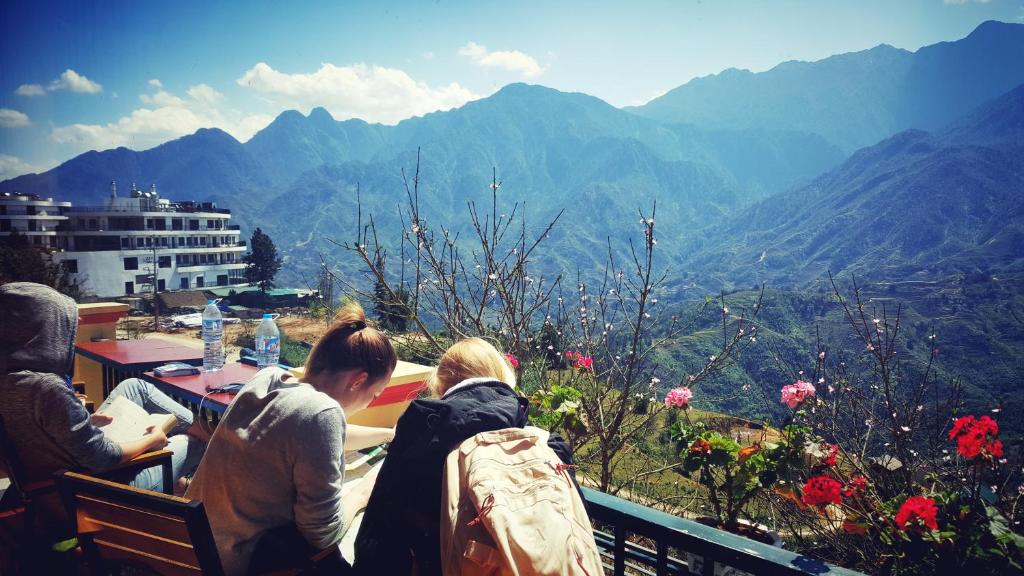 un groupe de personnes assises sur un banc donnant sur les montagnes dans l'établissement Sapa Odyssey Hostel, à Sa Pa