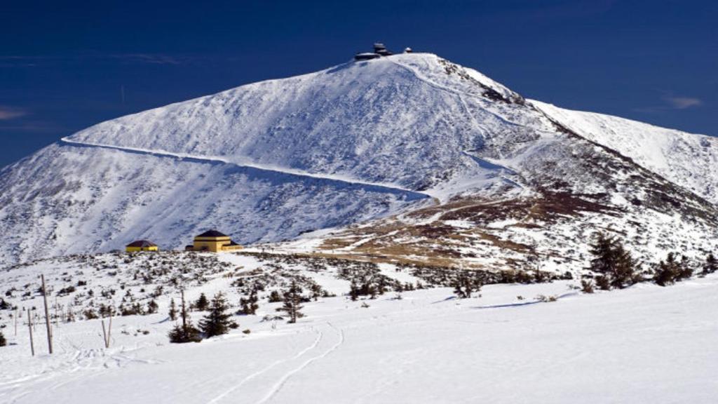 a snow covered mountain with a house on top of it at Apartament Panorama in Kowary