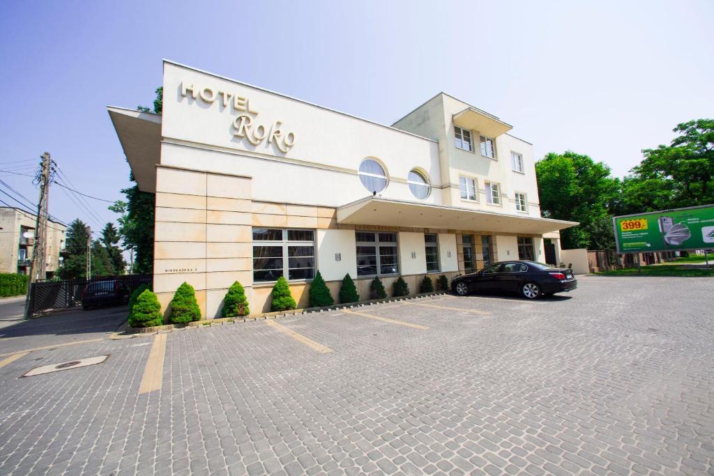 a building with a car parked in a parking lot at Hotel Roko in Warsaw