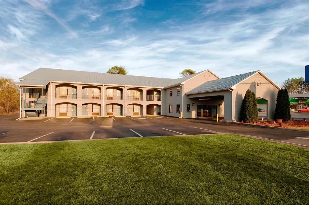 a large building with a parking lot in front of it at Americas Best Value Inn - Rome in Lindale