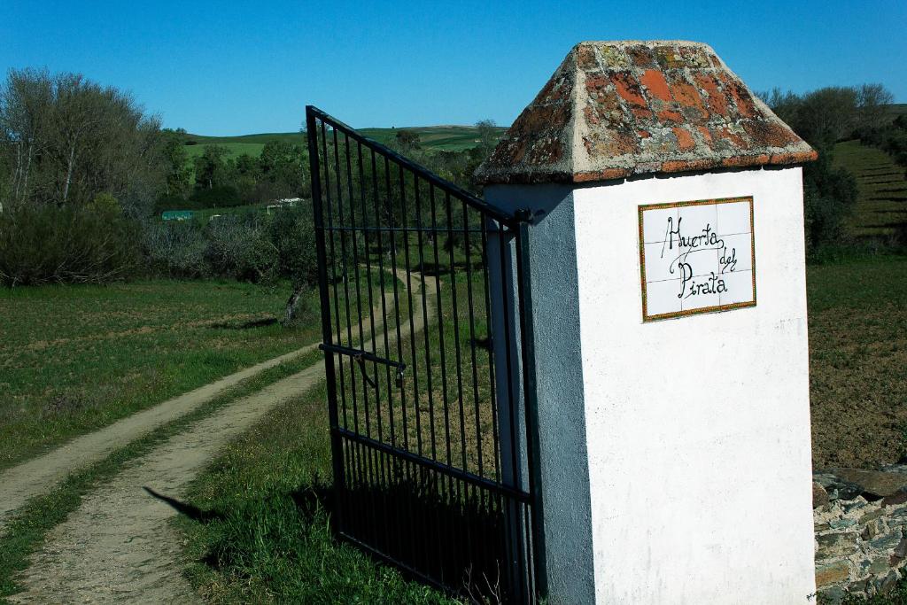a gate with a sign on it next to a road at Casa Rural Ecológica Huerta del Pirata in Fuente de Cantos