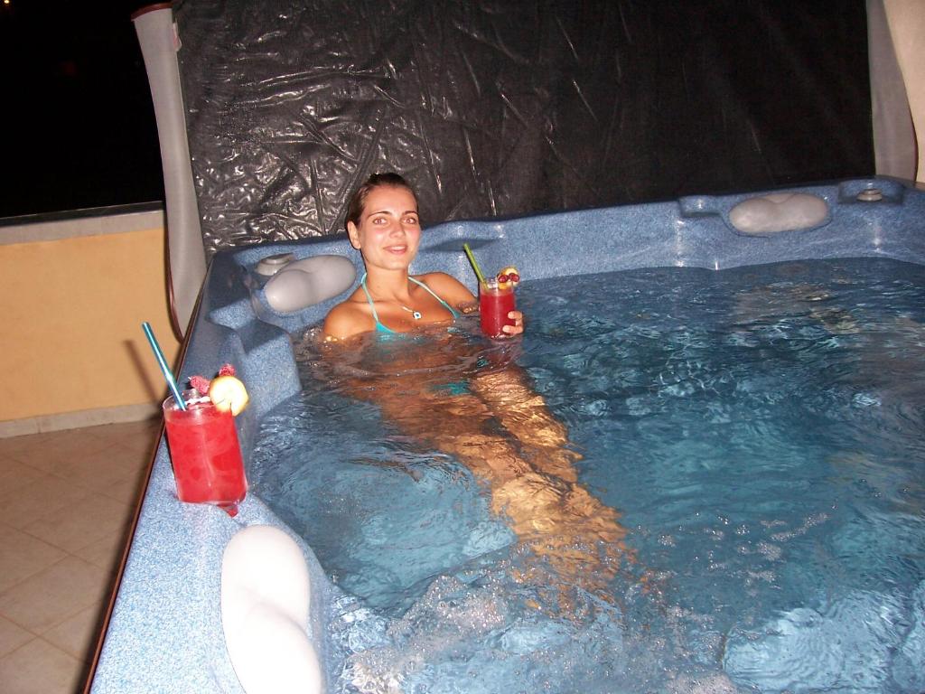 uma mulher sentada numa banheira de hidromassagem com bebidas em Villa Tunley em Medovo