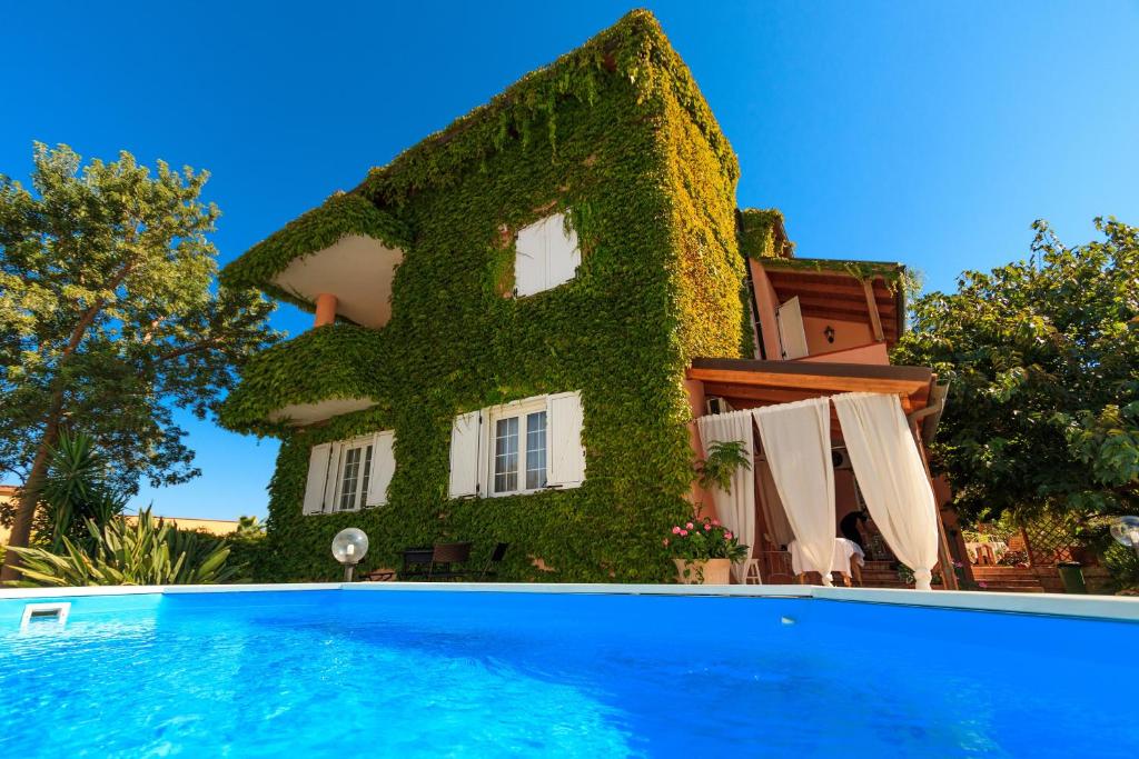 ein von Efeu bedecktes Haus neben einem Pool in der Unterkunft HB Le suites del Giardino in Taranto