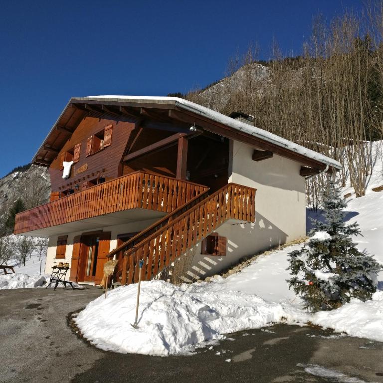 une cabane en rondins avec une terrasse dans la neige dans l'établissement Two Bedroom Apartement Belle Vue, à La Chapelle-dʼAbondance