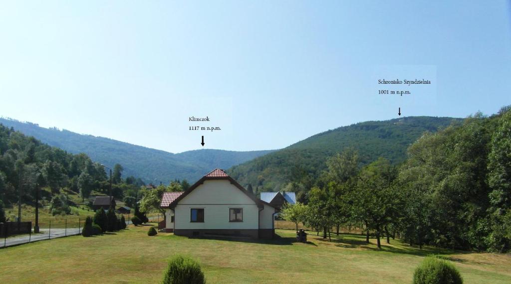 a house in a field with mountains in the background at Noclegi pod Klimczokiem in Bystra