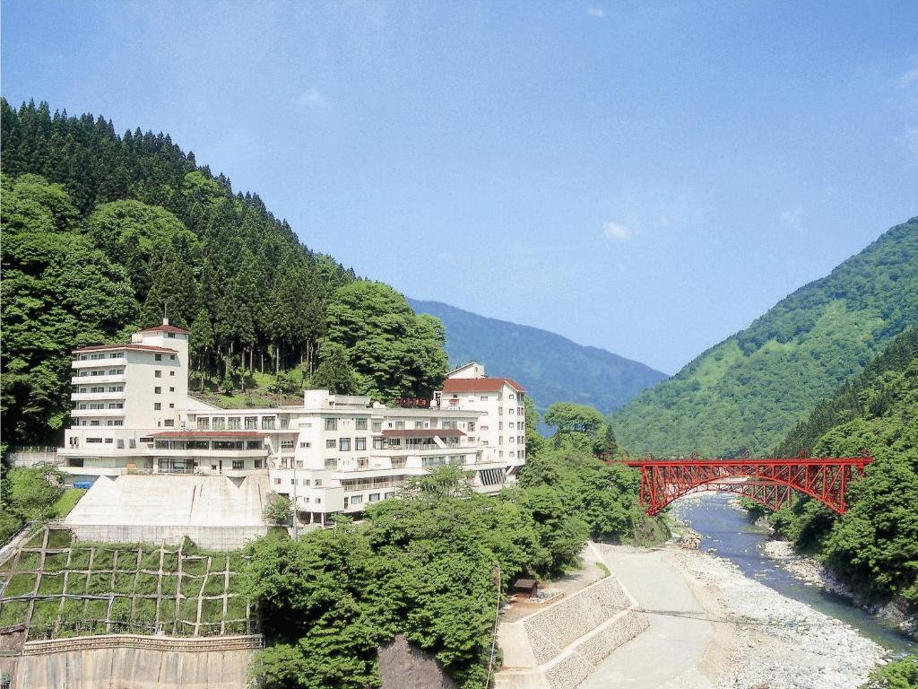 a red bridge over a river next to a building at Hotel Kurobe in Kurobe