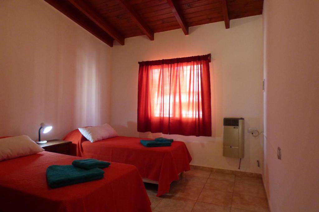 Zimmer mit 2 Betten und einem Fenster mit roter Bettwäsche in der Unterkunft Departamento Centrico Laprida in Cordoba