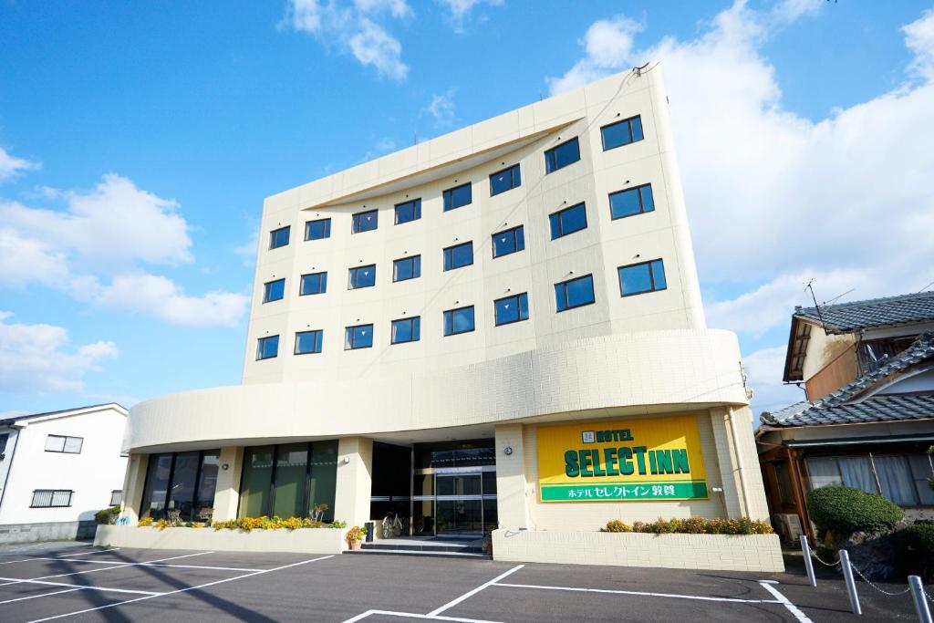 a large white building with a parking lot at Select Inn Tsuruga in Tsuruga