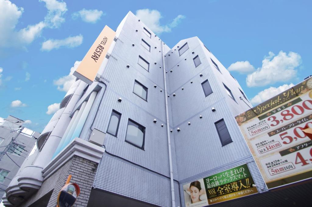 a white building with windows on the side of it at Restay Fuchu (Adult Only) in Fuchu