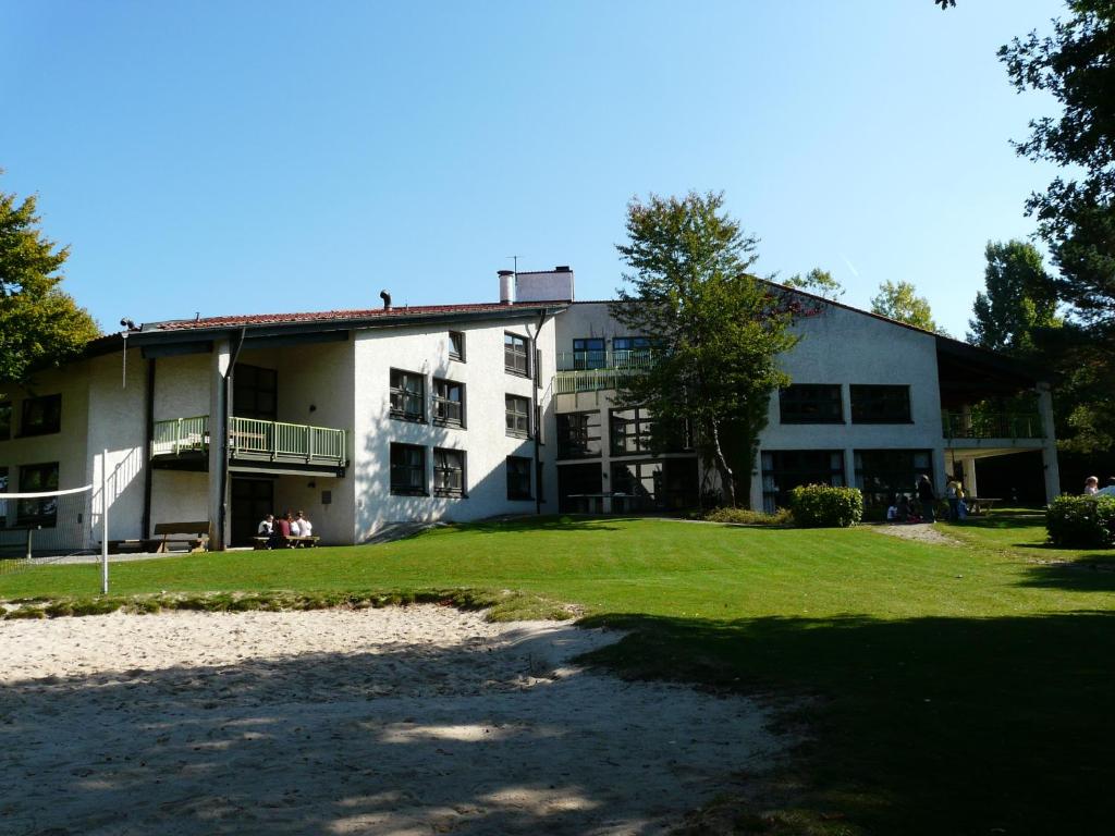 ein großes weißes Gebäude mit einem Hof davor in der Unterkunft DJH Jugendherberge Pottenstein in Pottenstein