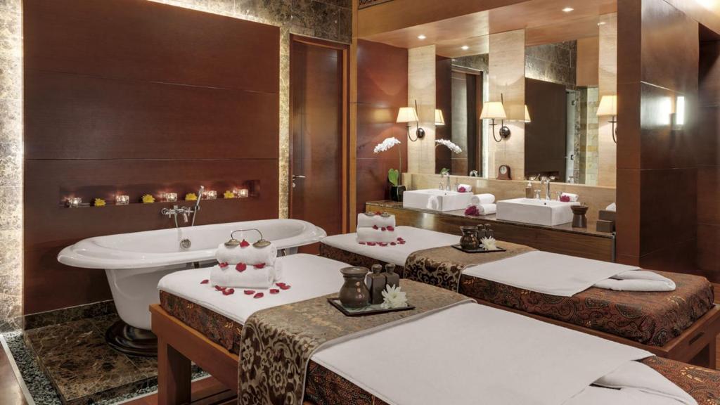 a bathroom with two sinks and a toilet and a tub at Hotel Indonesia Kempinski Jakarta in Jakarta