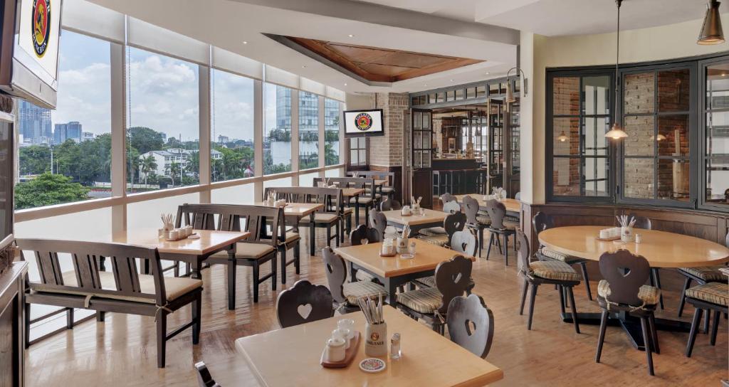 a restaurant with tables and chairs and large windows at Hotel Indonesia Kempinski Jakarta in Jakarta