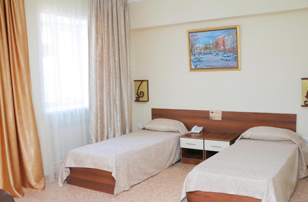 Habitación de hotel con 2 camas y ventana en Hotel Zumrat, en Karagandá