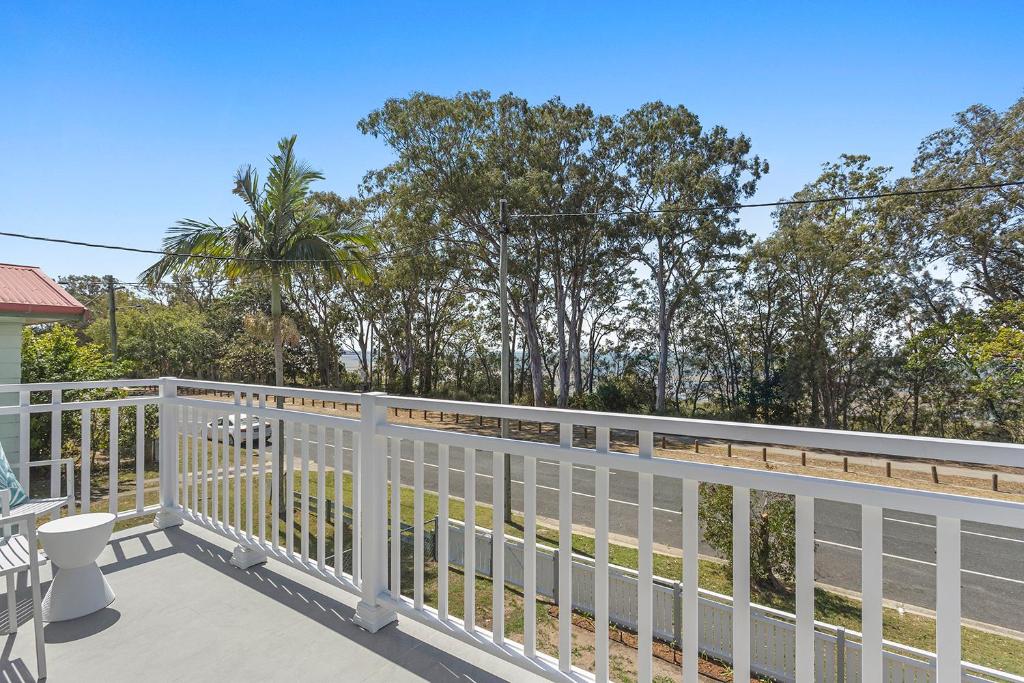 a balcony with a white fence and trees at Hamptons at The Bay in Deception Bay