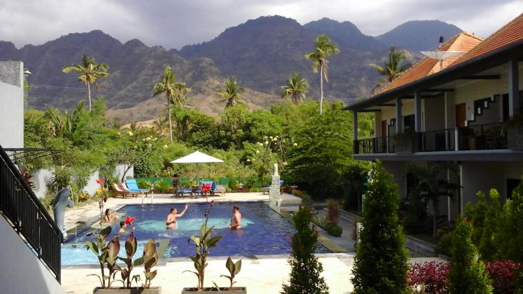 a group of people in a swimming pool with mountains in the background at Antari Hotel Pemuteran in Pemuteran