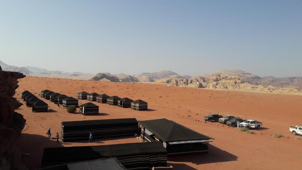 a group of black structures in a desert with vehicles at Wadi Rum Bedouin Way Camp in Wadi Rum