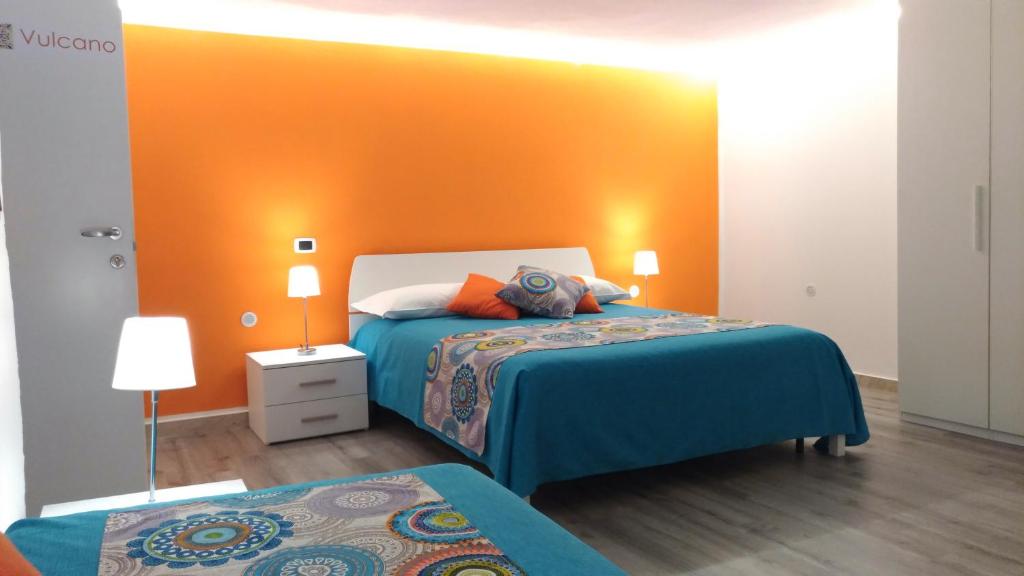 a bedroom with two beds and an orange wall at B&B Micucco in Milazzo