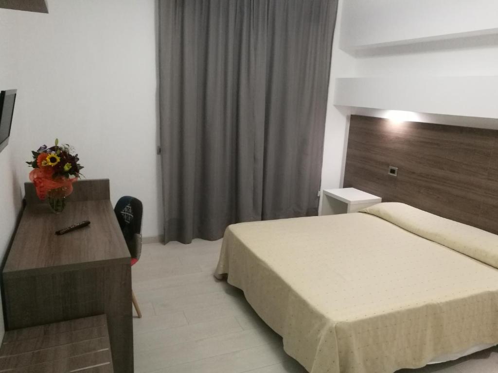 um quarto de hotel com uma cama e uma mesa com flores em Hotel Miramare em Cirò Marina