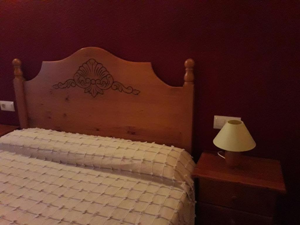 a bedroom with a bed with a wooden headboard and a lamp at Pati Curreu in Palanques