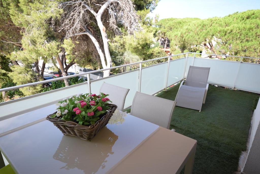 una mesa blanca con una cesta de flores en el balcón en Castelldefels Playa, en Castelldefels