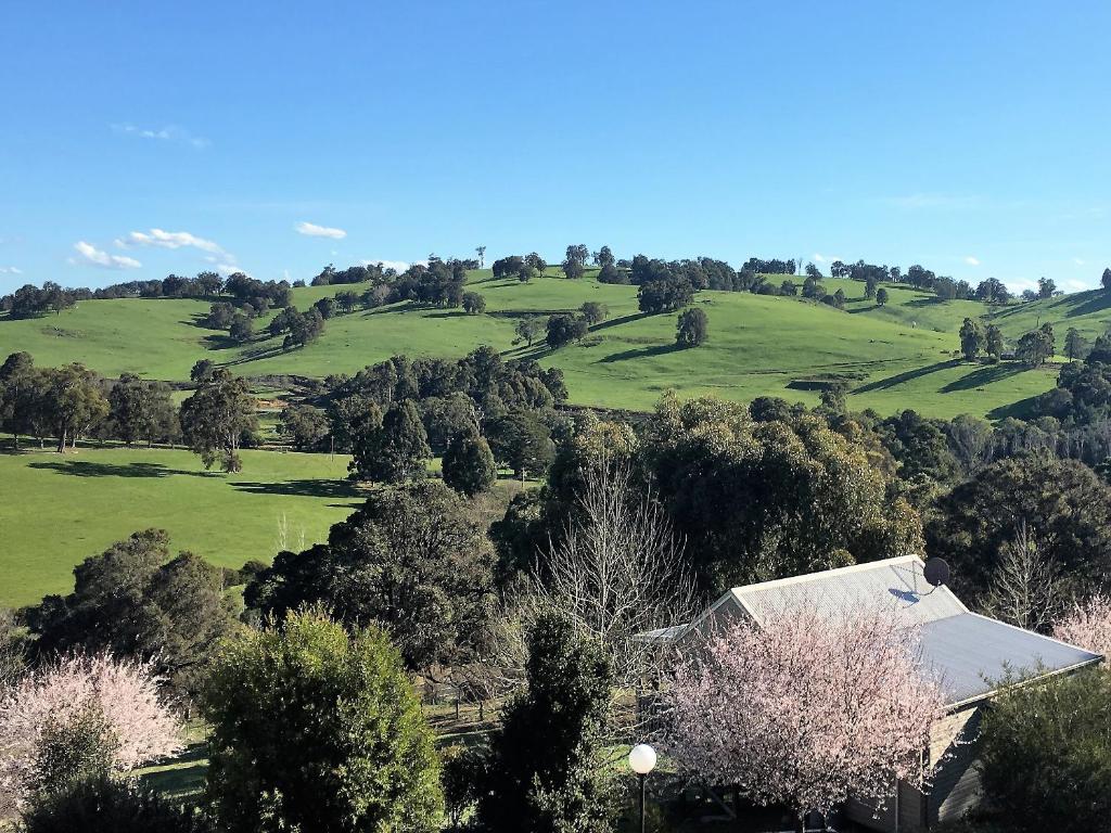 a house on a hill with green fields and trees at Balingup Highview Chalets in Balingup