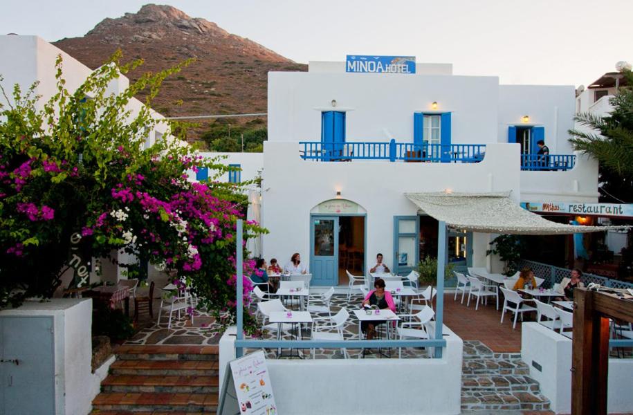 ein Restaurant mit weißen Gebäuden, Tischen und Blumen in der Unterkunft Hotel Minoa in Katápola