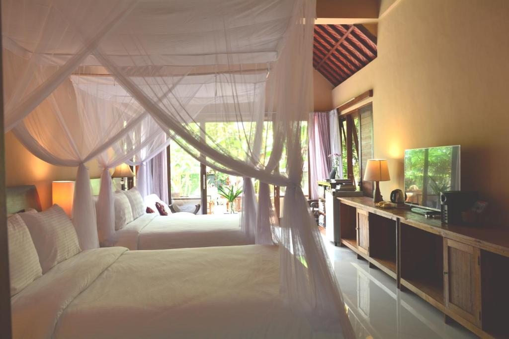 a bedroom with two white beds and a window at Griya Sriwedari in Ubud