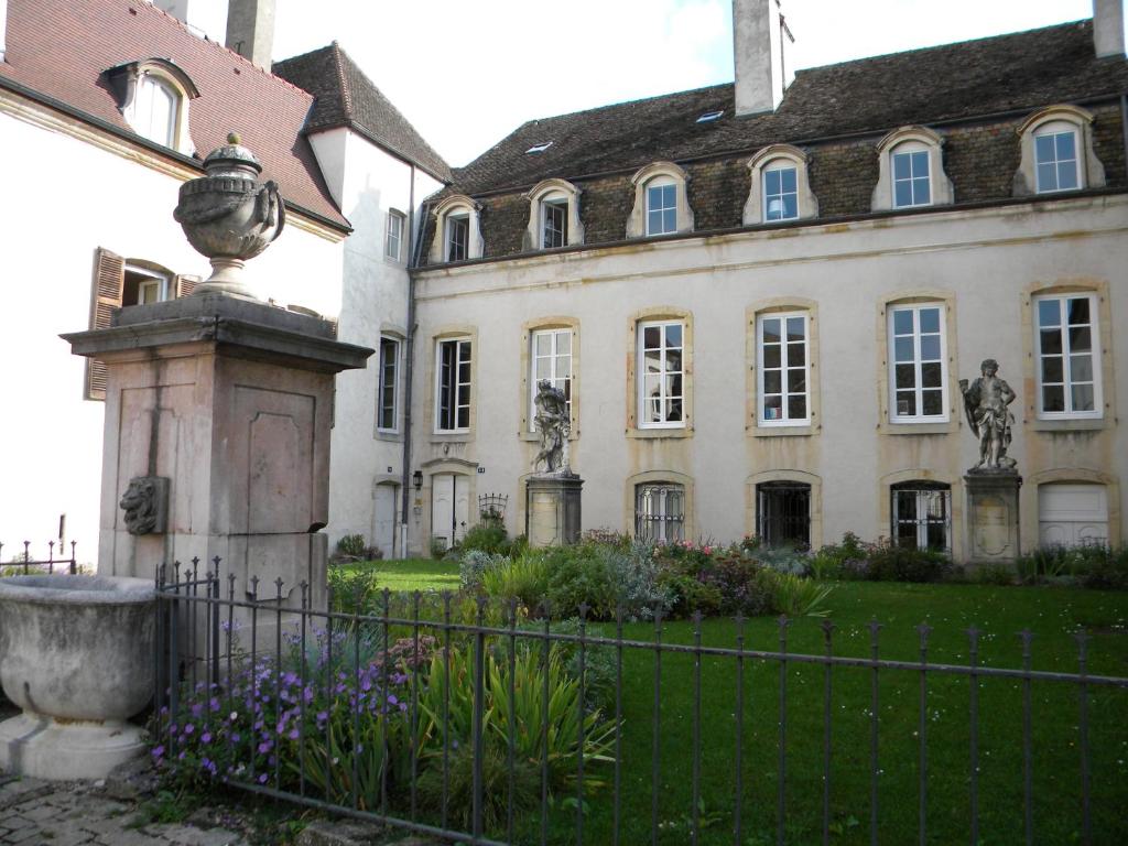 a house with a fence and a statue in front of it at Le jardin des chanceliers in Beaune