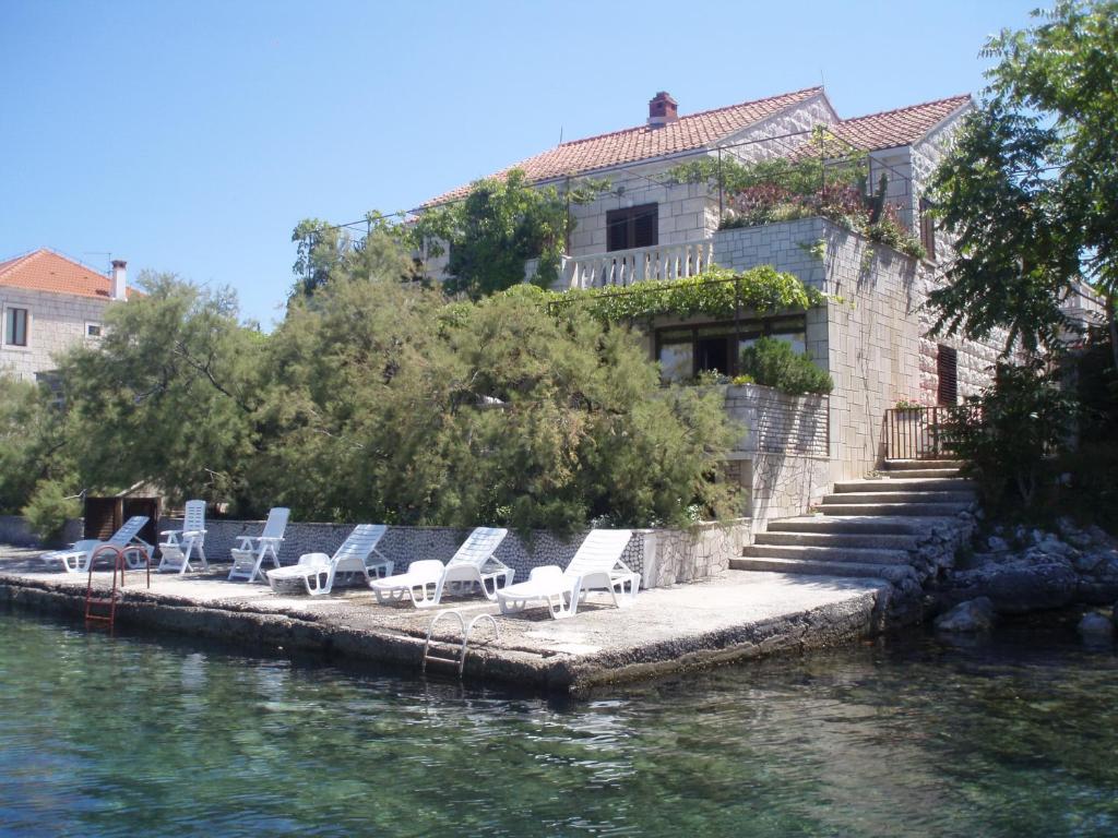 eine Sitzreihe auf einem Steg neben dem Wasser in der Unterkunft Stone house Gregov in Lumbarda